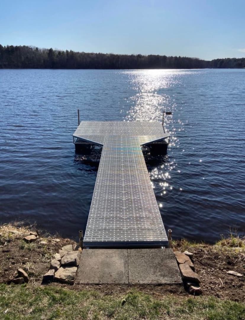Dock extending into a serene lake with shimmering water under a clear blue sky.